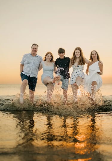 Family playing together in the shallow sea during a sunset family photography session at Jimbaran Beach Bali
