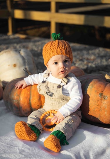 Super cute photo of baby boy in a pumpkin patch, dressed as a pumpkin.