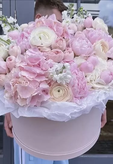 a man holding a large pink flower in a hat box