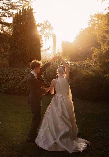 A bride and groom dancing in a garden during a golden hour sunset wedding photoshoot.
