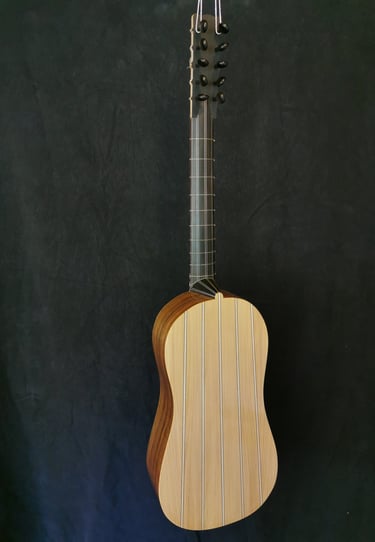 Handcrafted Baroque guitar with striped wooden back and long fretboard against a dark background.