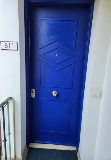 Modern vibrant blue entry door with geometric wood panels and house number 811 on white wall.