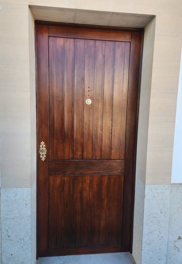 Traditional dark walnut stained wood front door with vertical panels and brass hardware.