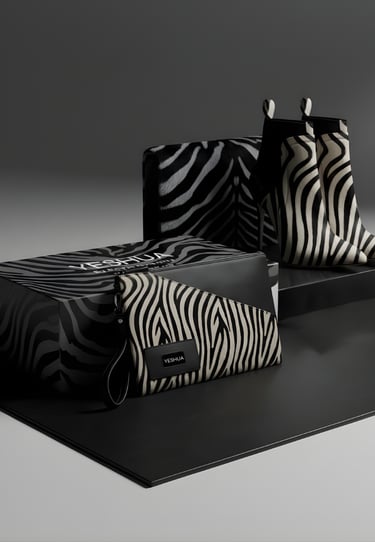 Luxury zebra print fashion set featuring pointed-toe ankle boots, a matching clutch bag, and a designer gift box.