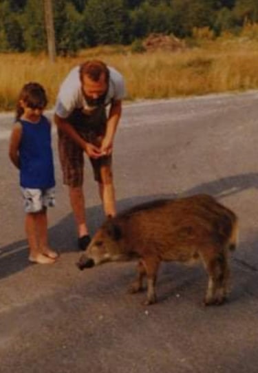 A man and a young child with a wild pig