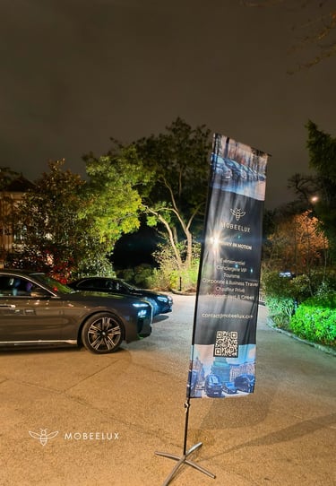 Luxury chauffeur service sedan parked at night next to a MOBEELUX promotional banner.