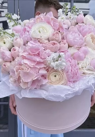 a man holding a large pink flower in a hat box