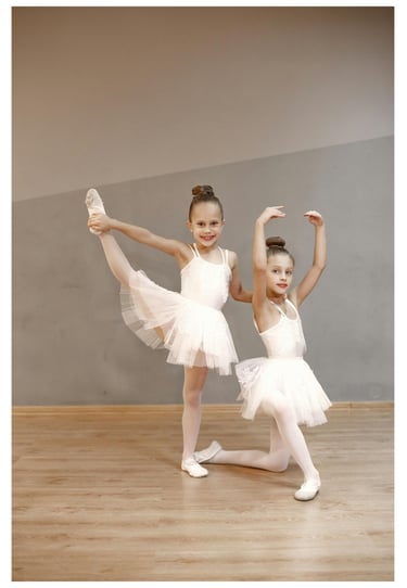 two young girls having fun in white dresses are posing for a photo