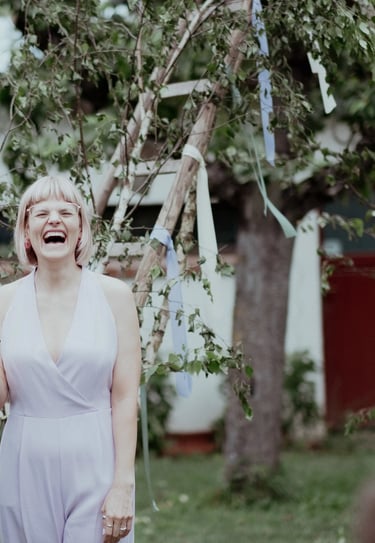 Traurednerin Silke lacht während einer freien Trauung und hält eine persönliche Rede mit Mikrofon im Freien.