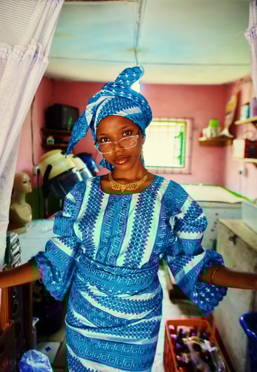 An Young African woman in a blue lace dress standing at the entrance of a room
