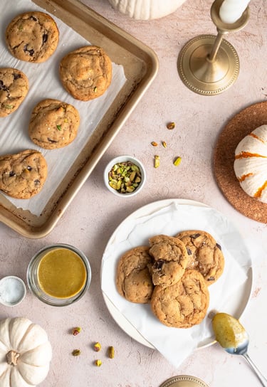 a tray of pistachio chocolate chip cookies with a plate of cookies and pistachios