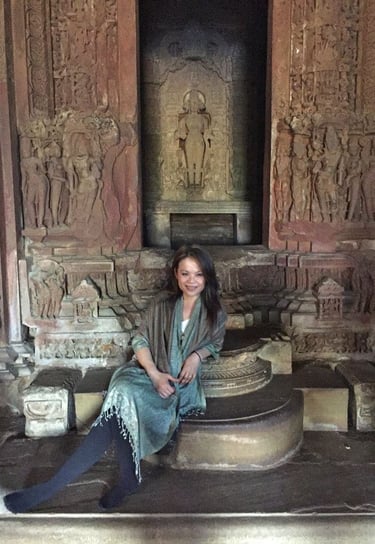 a woman sitting on a stone step with a statue of a woman