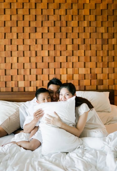 Family cuddling together on the bed during a cozy lifestyle family session at Anantara Uluwatu.