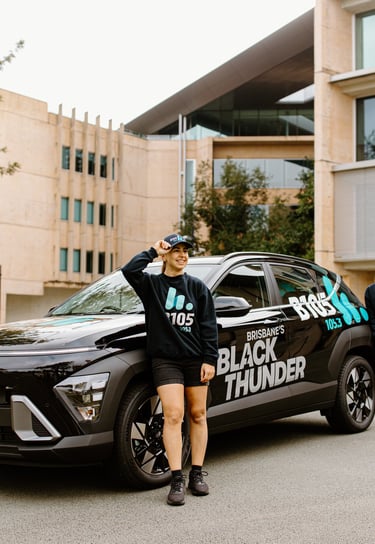 a woman from B105 standing next to a Hyundai Kona with a man in a black shirt