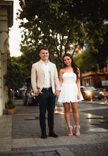 a man and woman holding hands and walking down the street