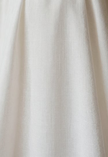 Macro photography of an elegant baptismal gown made of fine white linen, soft textures, minimalist and clean composition, European / Spanish traditional aesthetic, bright off-white tones.