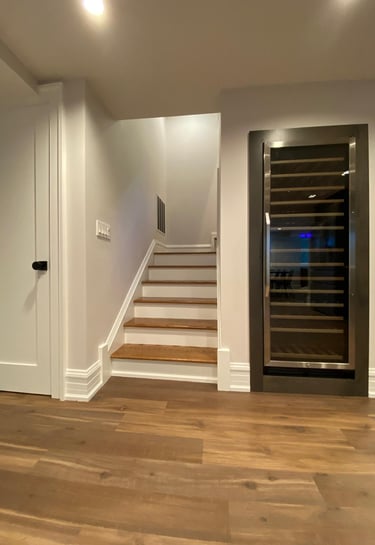 Finished basement featuring staircase with wine cooler installed under the stairs