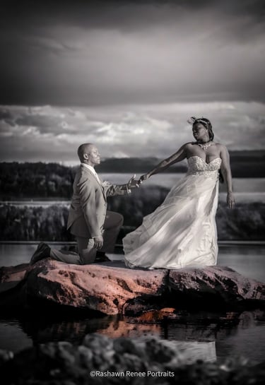 a bride and groom holding hands on a rock posing for wedding portraits
