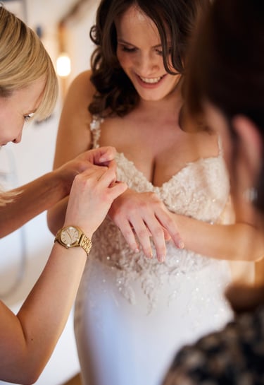 Close-up of a bride and groom's hands with gold wedding bands resting on a floral bouquet.