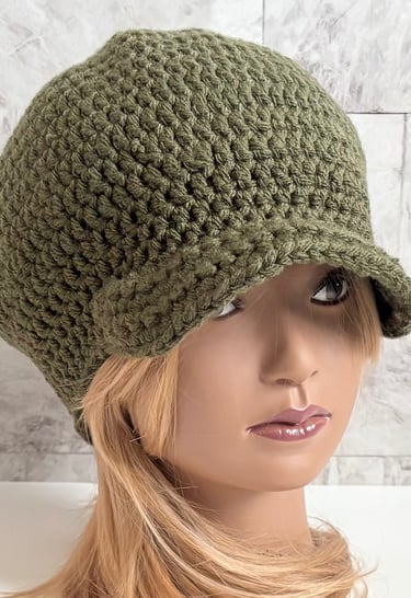 Woman wearing an olive green brimmed crochet Newsboy cap.