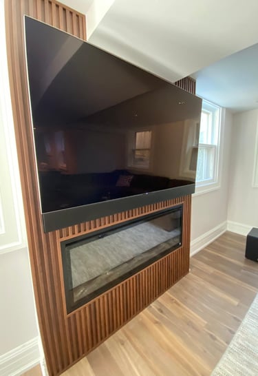 Finished basement with built-in shelving, electric fireplace, and TV above