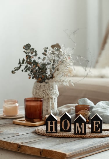Cozy home decor setup with candles, dried flowers, and wooden 'HOME' blocks on a rustic table