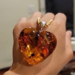 a person holding a heart shaped necklace with a heart shaped pendant
