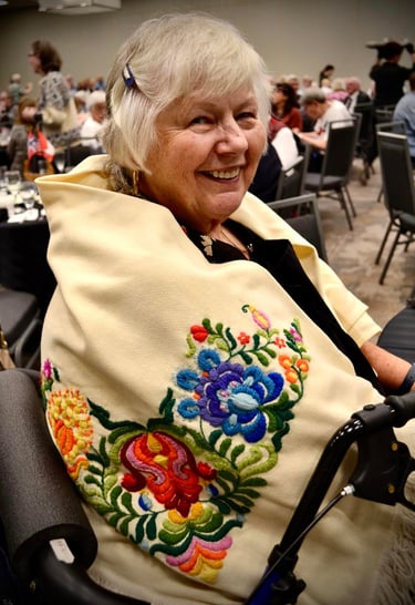 a smiling woman with an embrodiered shawl