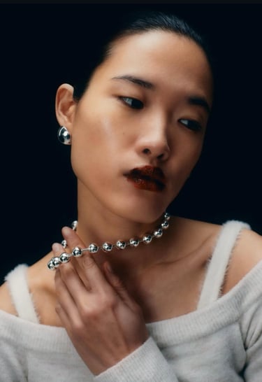 a woman wearing a necklace and a necklace with a necklace with a chain link