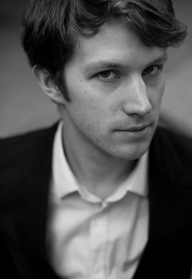 A black and white headshot of a man in a white shirt.