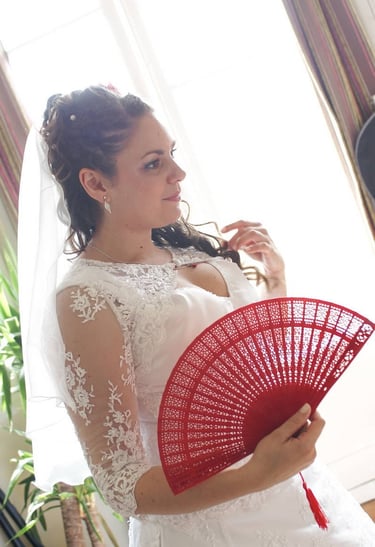Photo de mariée en robe avec un éventail rouge et un voile.