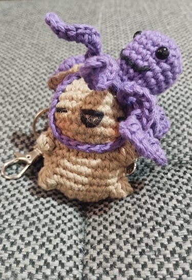 Llavero de amigurumi hecho a mano, tejido a crochet, con un capibara color canela y un pulpo morado.