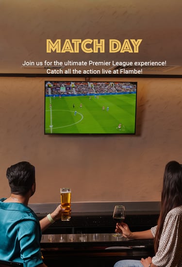 A couple enjoys drinks at a bar while watching a live Premier League match on a wall-mounted TV