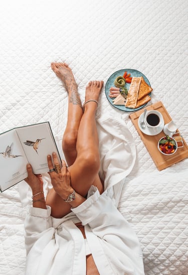 a woman is laying on a bed with a book and a plate of food in her bedroom of a hotel in costa rica