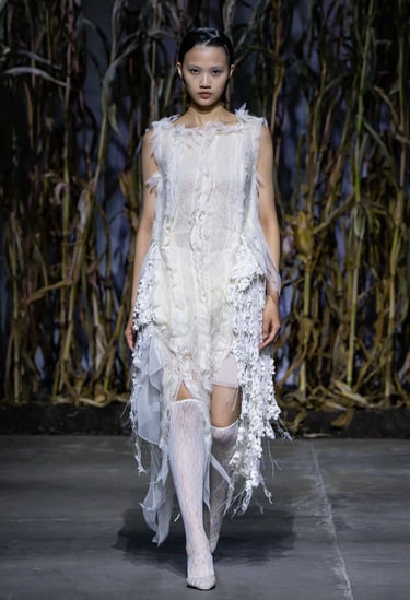 a woman in a white dress and stockings on a runway