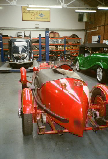 a classic car garage with three vintage cars parked in it
