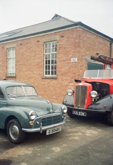 two classic cars parked in front of a brick building