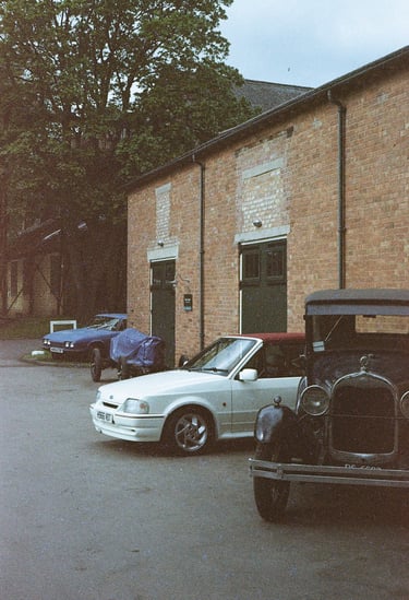 a selection of classic cars parked in front of a brick building