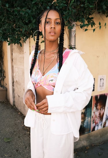 portrait d'une femme noire avec brassière colorée et pantalon ample blanc