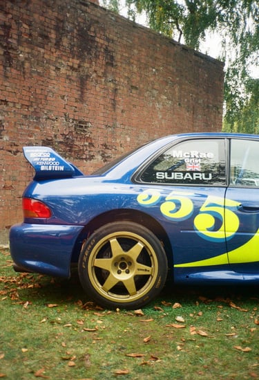 a Subaru Impreza rally car parked in front of a brick building