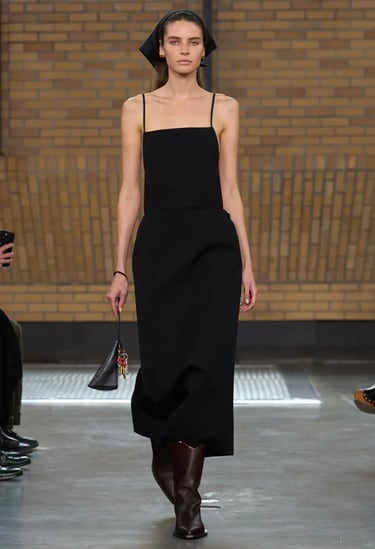 Calvin Klein Spring Summer 2026 runway model in sleek black slip dress with headscarf.