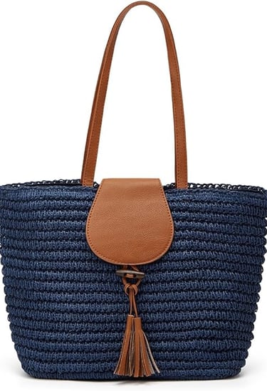 Navy blue woven straw tote bag with brown faux leather handles and a tassel accent for summer fashion.