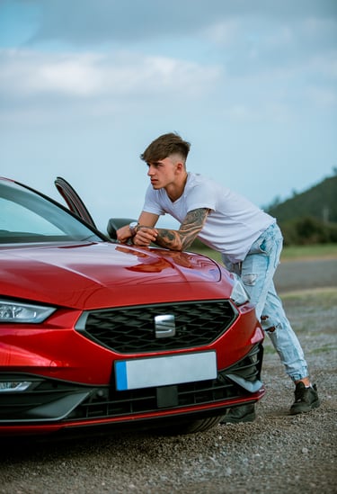 Sesión de fotos diurna con modelo en camiseta blanca junto a un Seat León rojo en un ambiente urbano