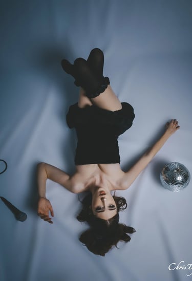 Shooting femme en robe noire allongée tête en bas avec un micro et une boule à facettes à perpignan 