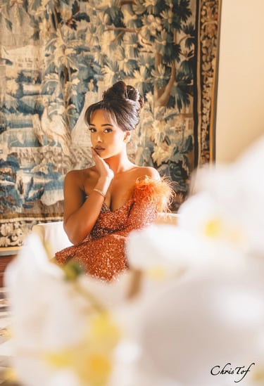 Photographie d'une femme en robe de soirée orange à paillettes posant devant une tapisserie à Valmy