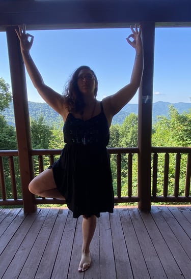 Rachel on balcony doing yoga with mountain range and tall trees and background