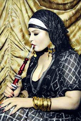Lovely Bellydancer Fifi Abdou in Egyptian Assuit wearing headscarf and gold jewelry smoking a hookah