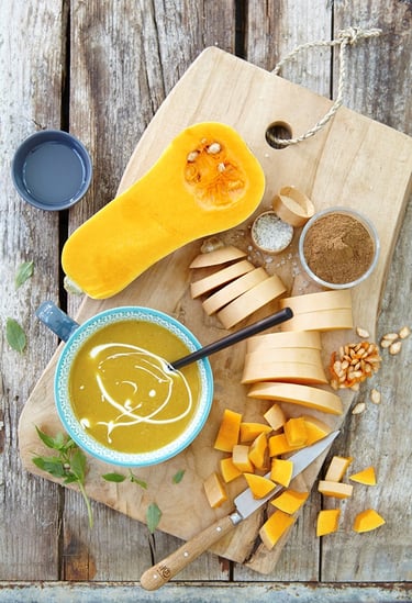 a wooden cutting board with a bowl of soup and a knife