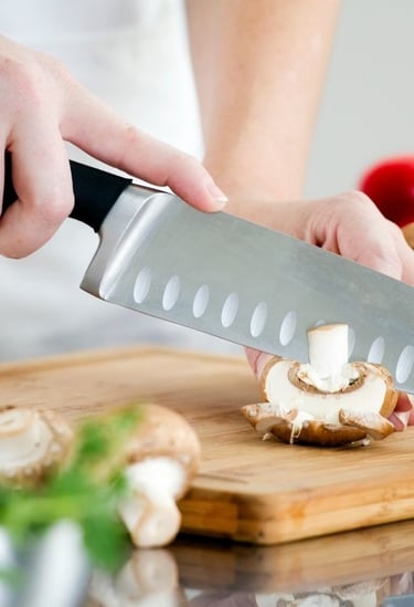 a person holding a knife and a knife in front of a cutting board