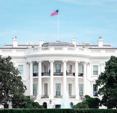 white house - a large white house with a flag on top of it